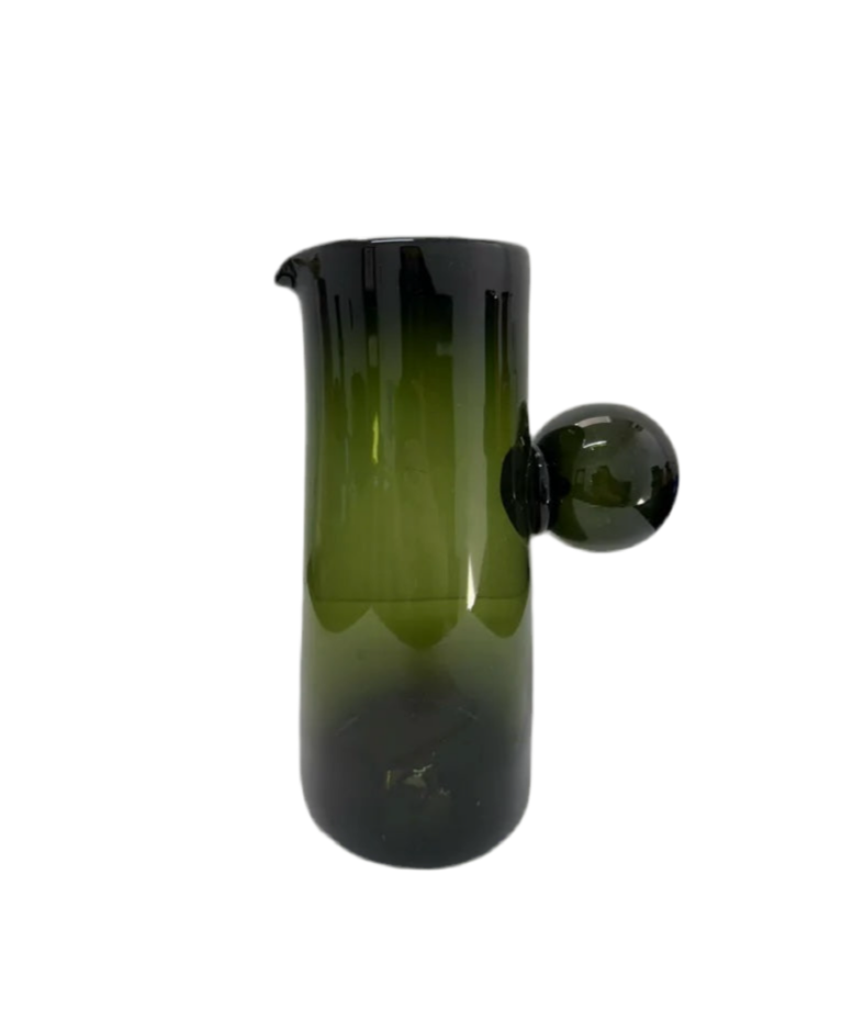 Green glass pitcher with a black handle on a white background