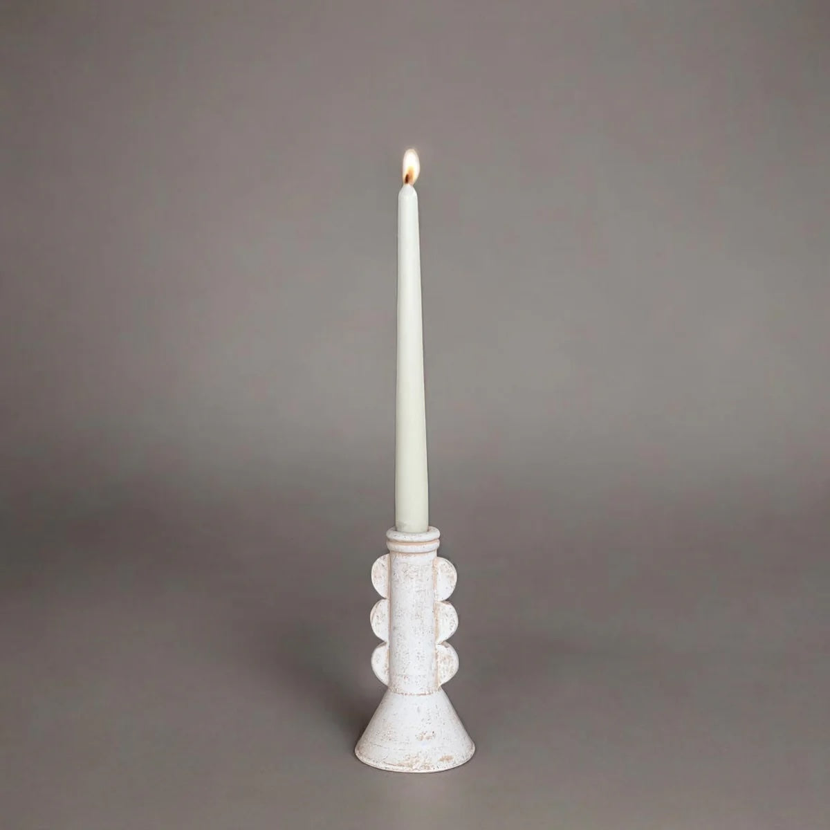 White candle in a decorative holder on a gray background