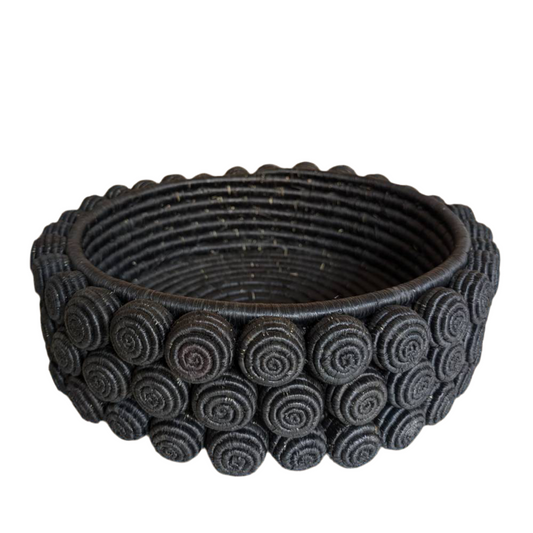 Black woven basket with circular patterns on a white background