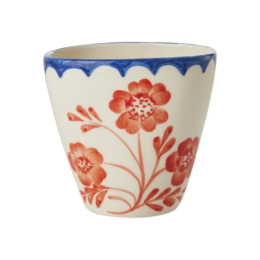 Ceramic cup with red floral design and blue rim on a white background