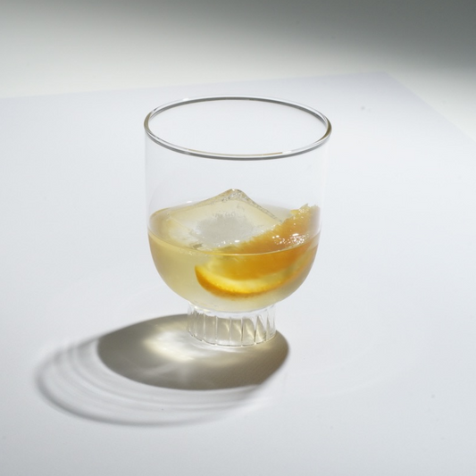 Clear glass with a cocktail and orange slice on a white background