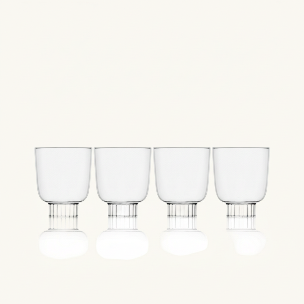 Set of four clear glass tumblers with metal bases on a white background