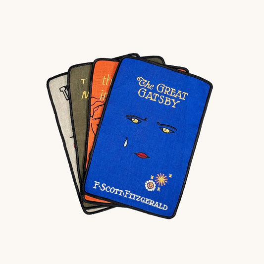 Stack of 'The Great Gatsby' book covers with a blue cover featuring a face design.