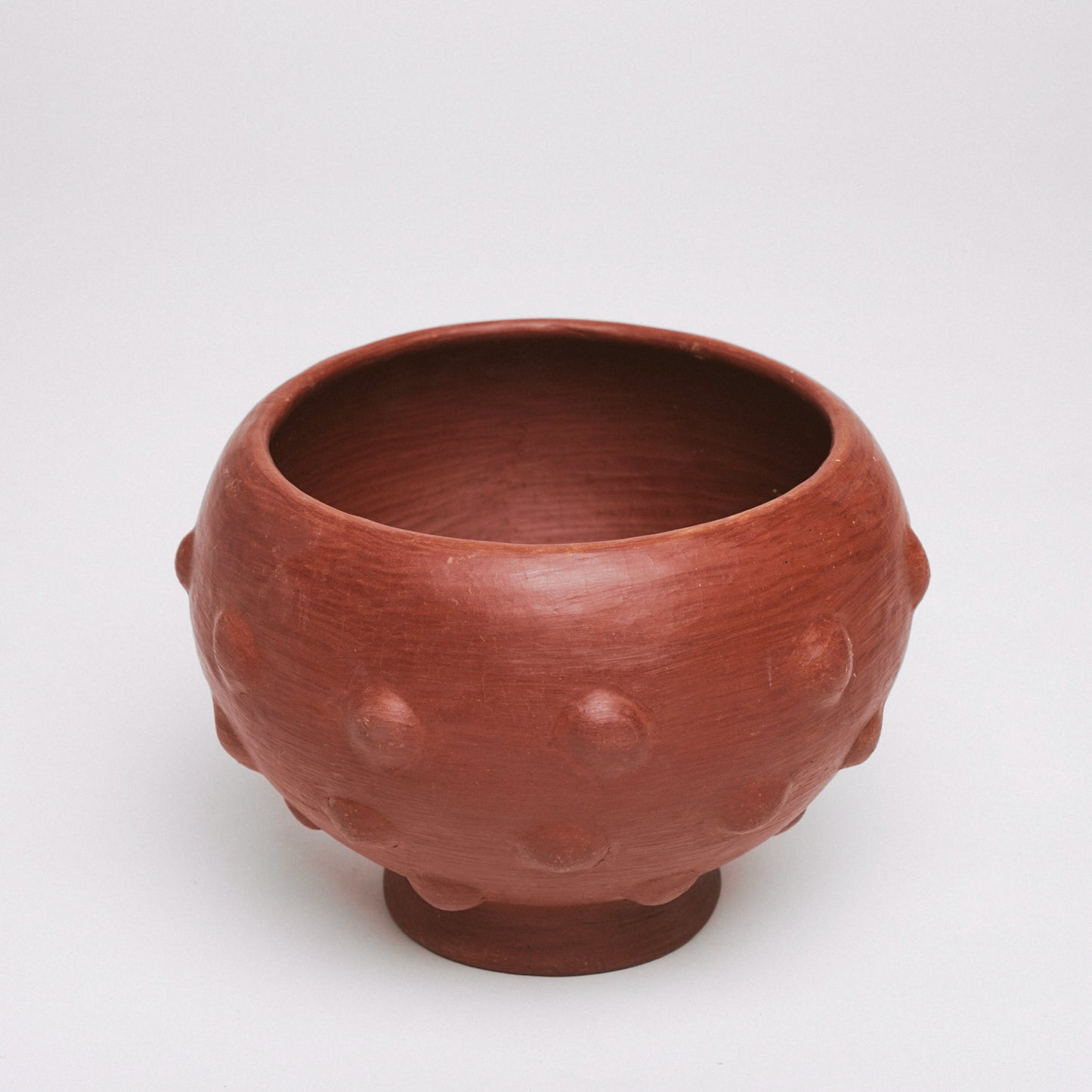 Red ceramic bowl with textured surface on a white background