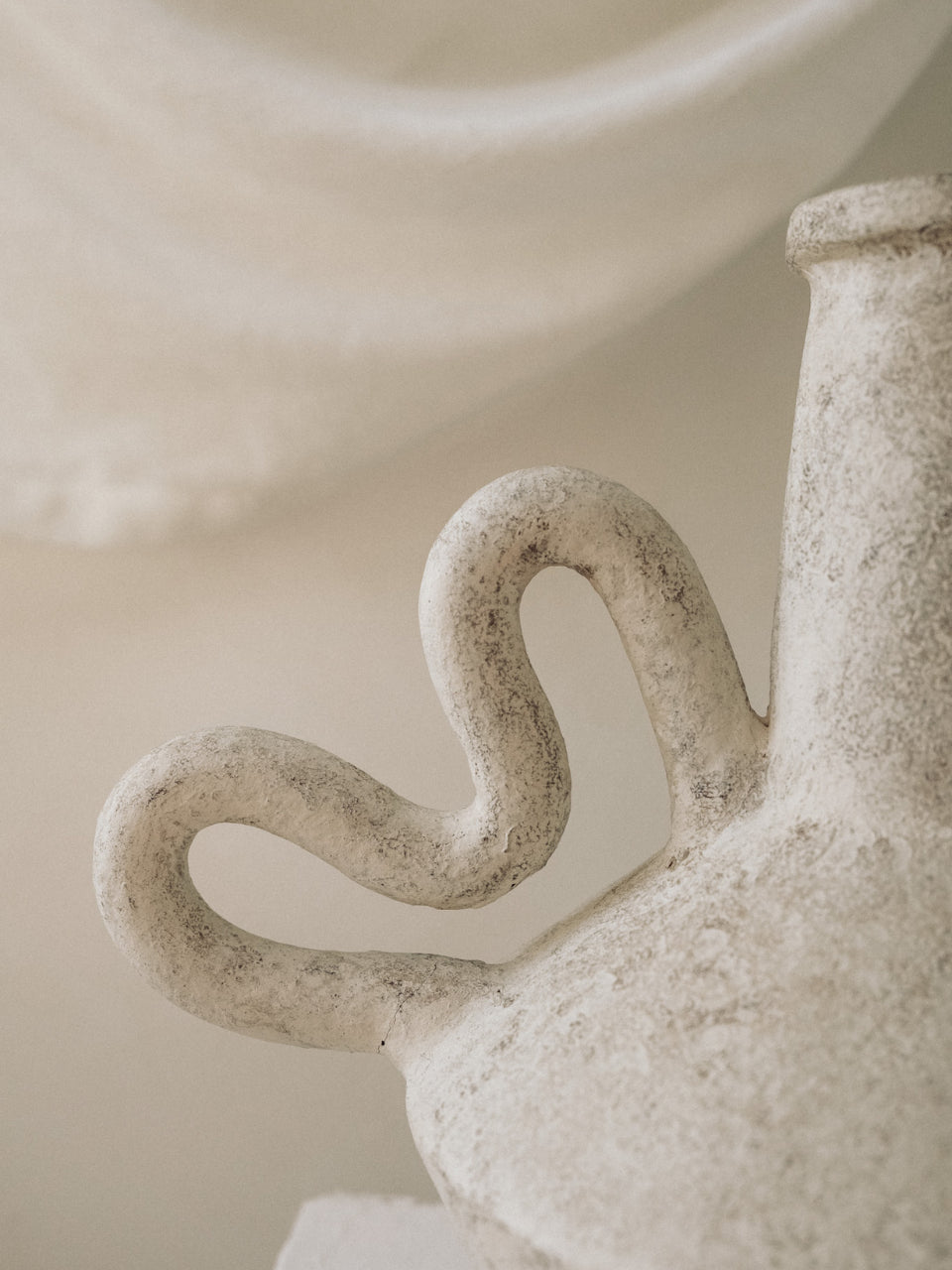 Close-up of a textured ceramic vase with a decorative handle.