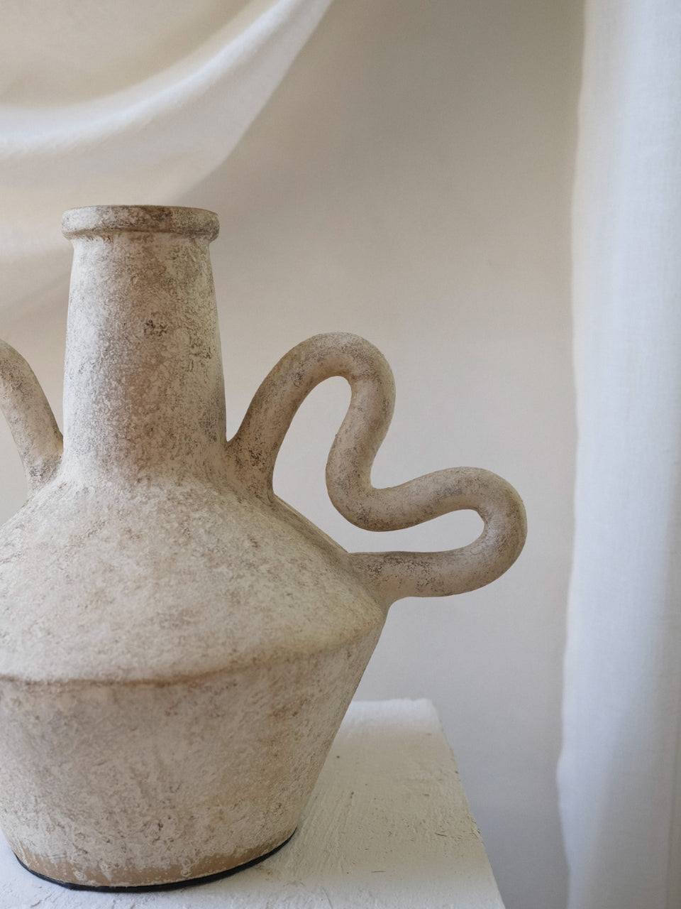 Ceramic vase with handles on a white surface and background