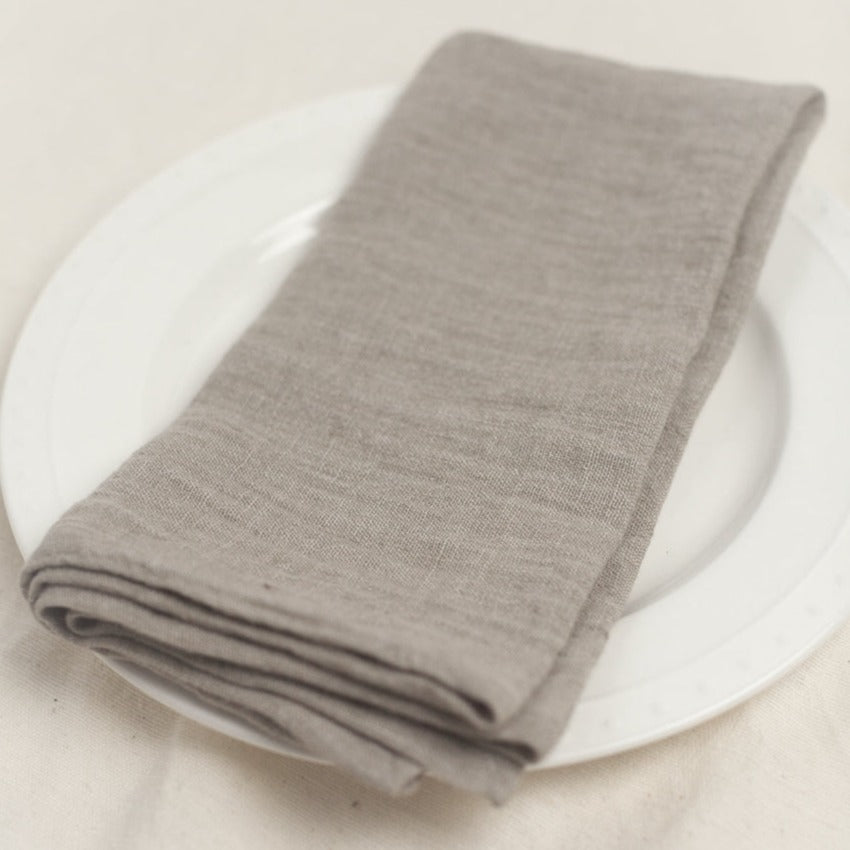 Folded gray napkin on a white plate with a light background