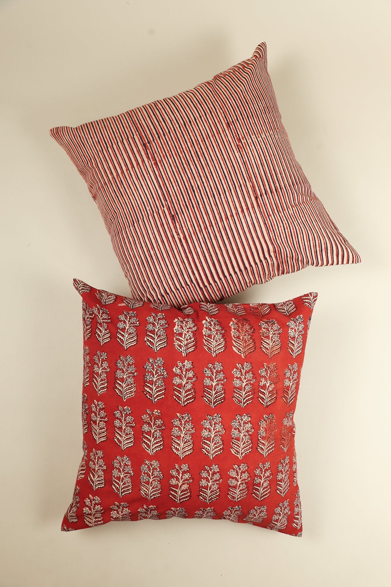 Two decorative pillows, one with red and white stripes and the other with a floral pattern on a beige background.