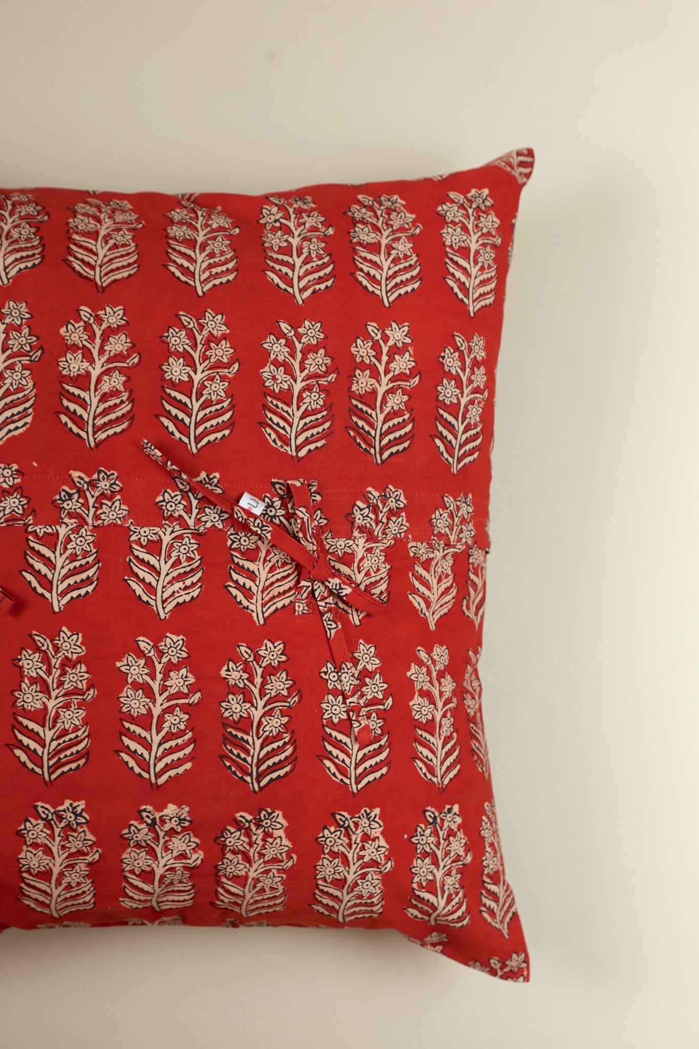 Red pillow with white floral pattern on a white background