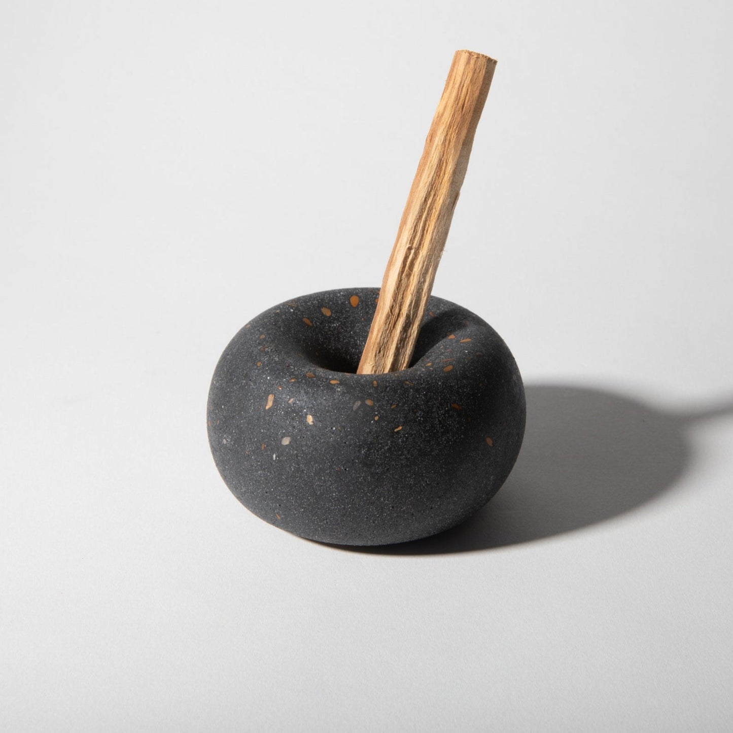 Black ceramic holder with a wooden stick on a light gray background