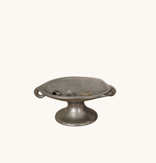 Metallic pedestal dish with shell designs on a white background