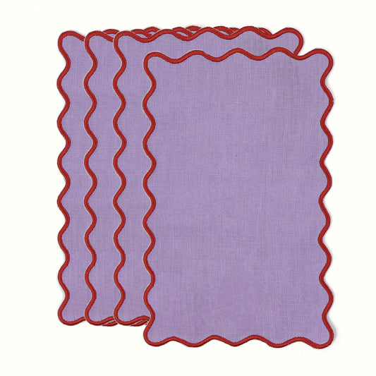 Set of three purple placemats with red scalloped edges on a white background