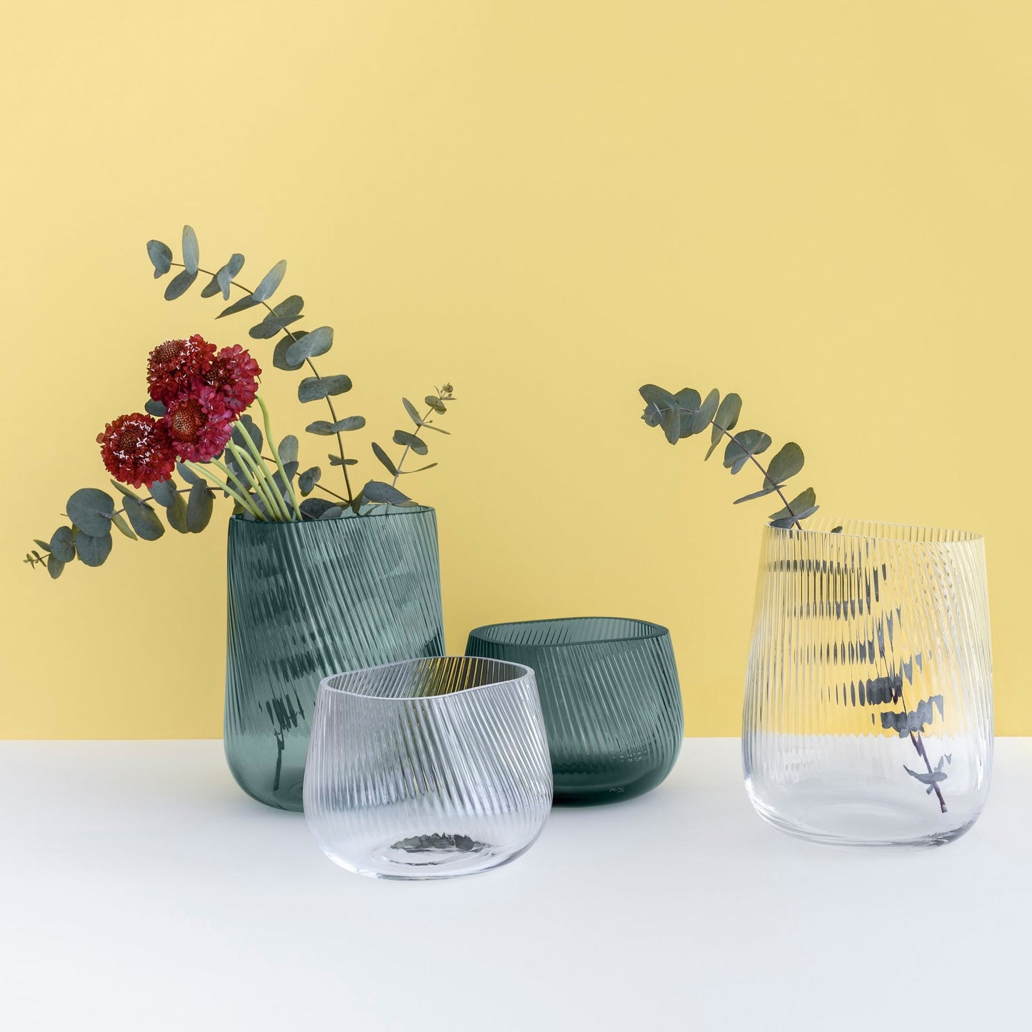 Set of glass vases with floral arrangements on a yellow background