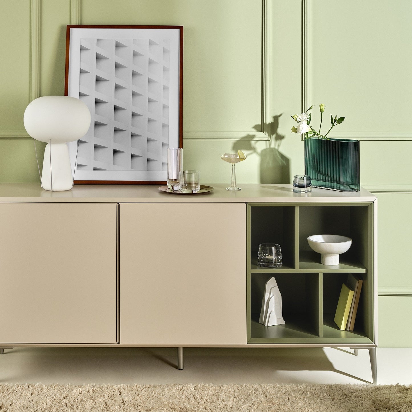 Modern interior with a light-colored cabinet against a green wall, featuring decorative items.
