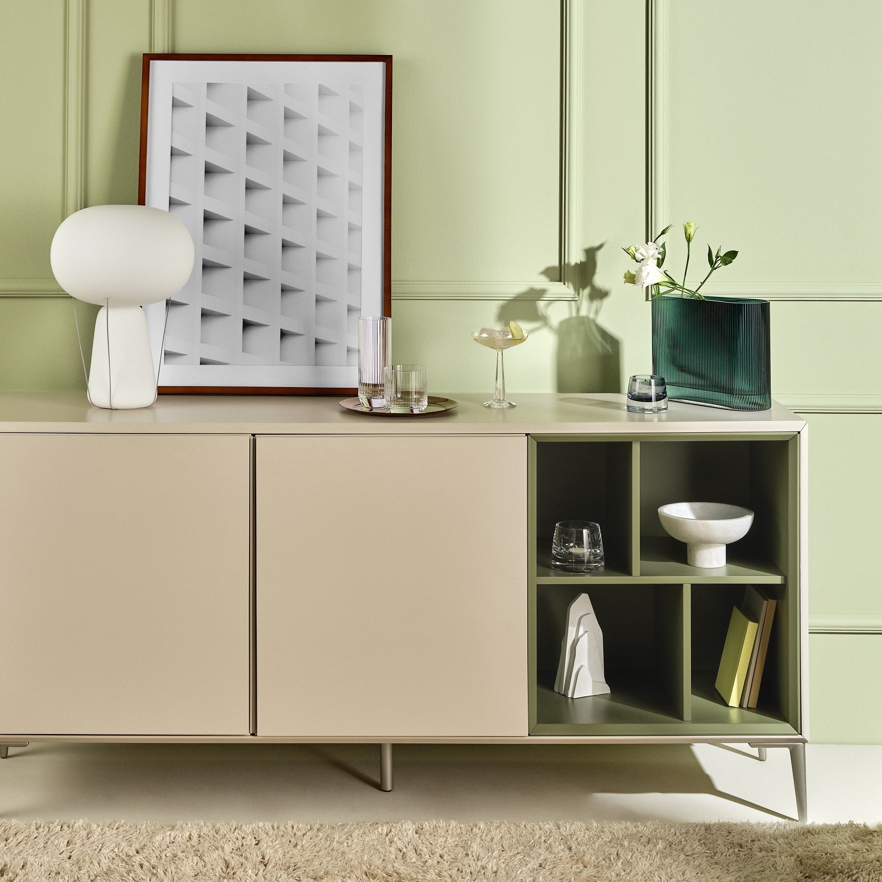 Modern interior with a light-colored cabinet against a green wall, featuring decorative items.
