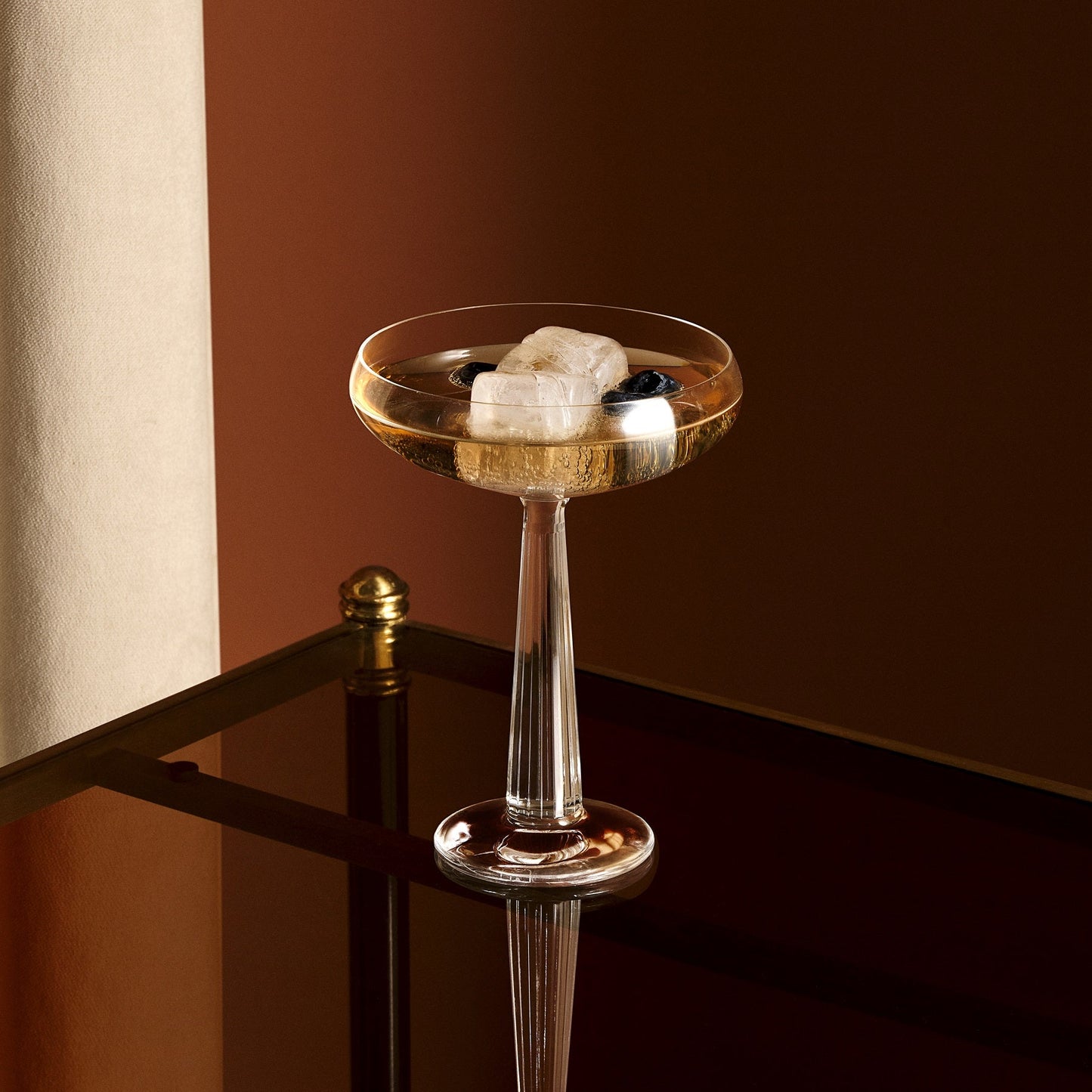 Clear glass bar cart with a brown background