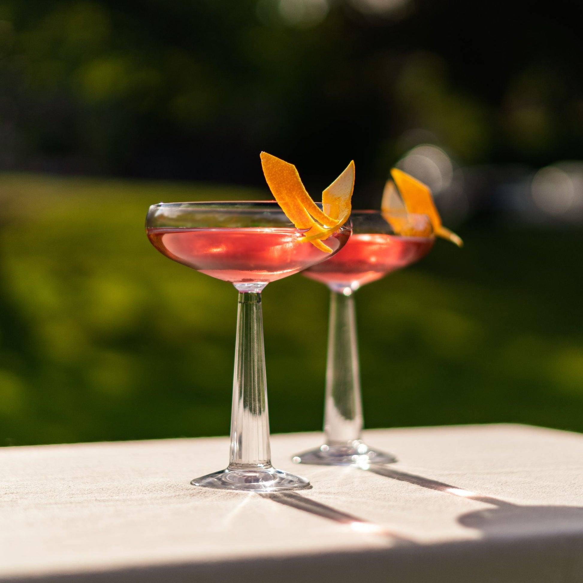 Two cocktails with orange slices on a table outdoors