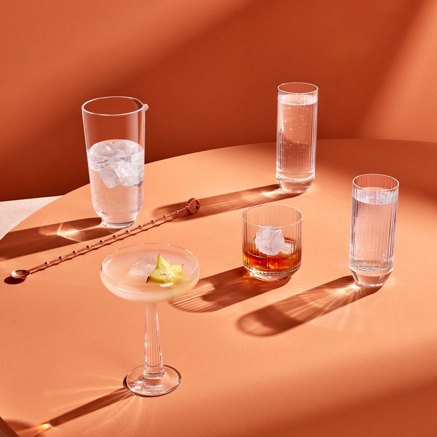 Cocktail glasses with different drinks on a peach-colored surface