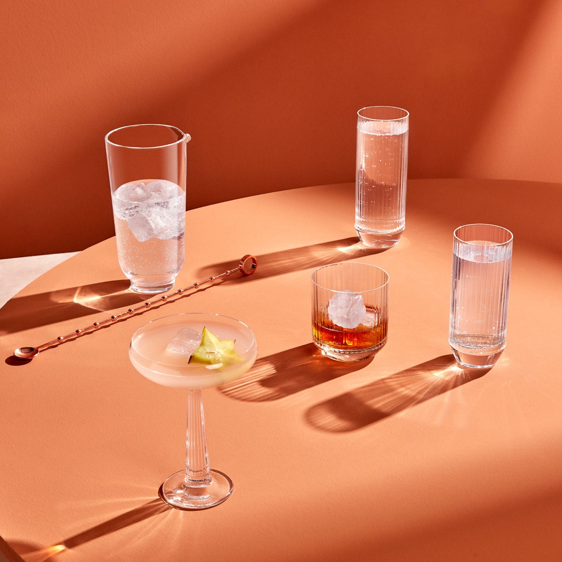 Cocktail glasses with different drinks on a peach-colored surface