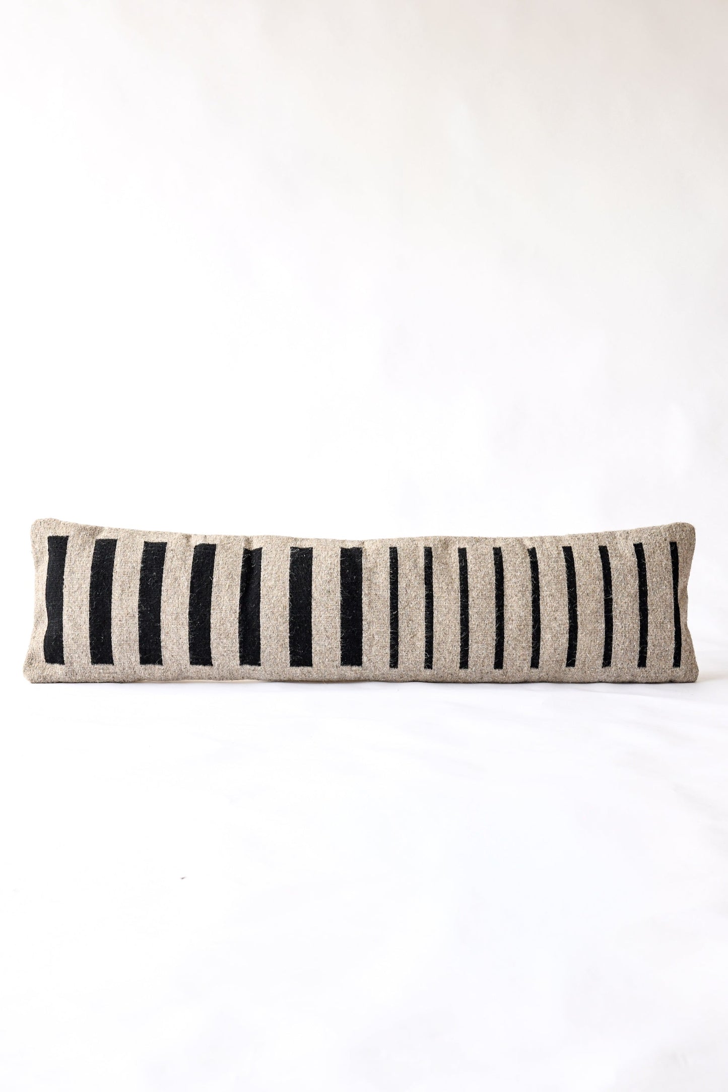 Striped pillow with black and beige pattern on a white background