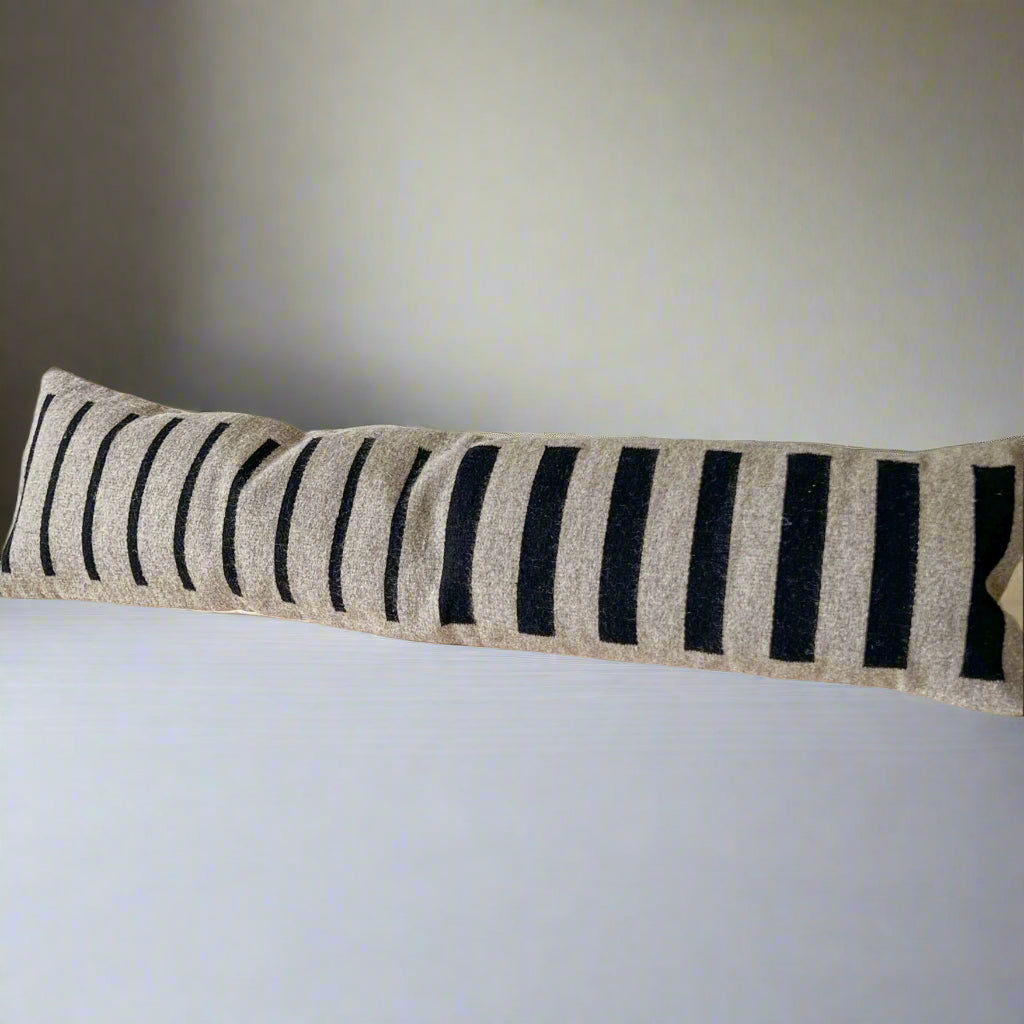 Long rectangular pillow with black stripes on a neutral background
