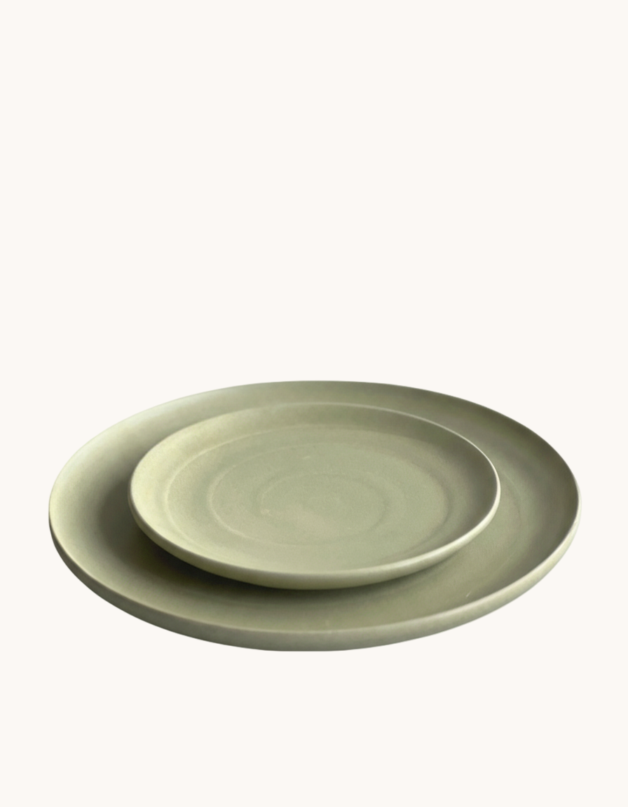 Two green ceramic plates stacked on a white background