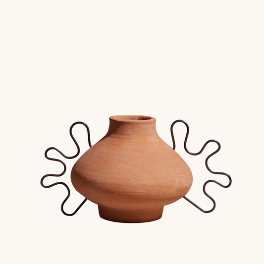 Terracotta vase with a decorative metal stand on a white background
