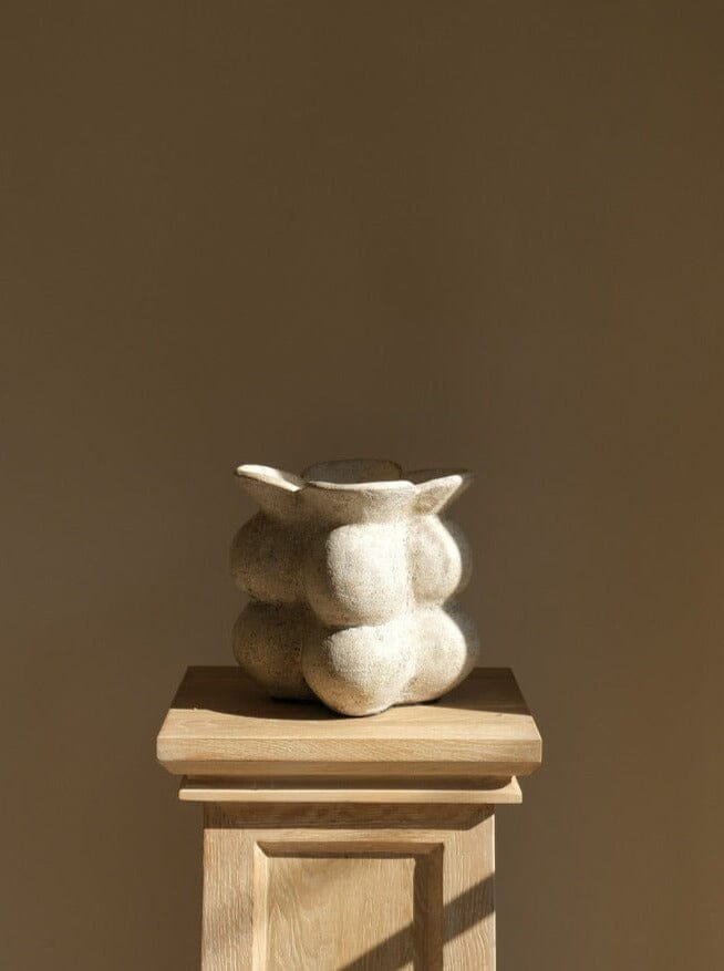 Decorative stone sculpture on a wooden pedestal against a brown background
