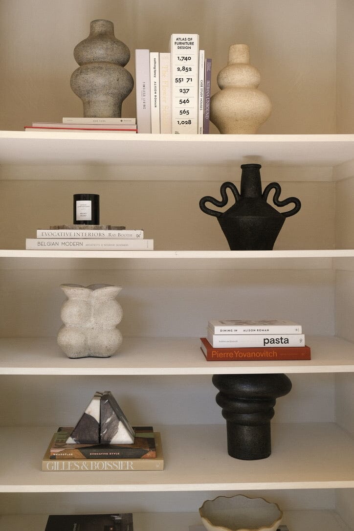 Decorative shelves with books and sculptures on a neutral background
