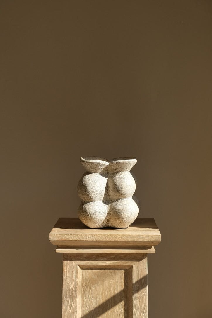 Ceramic sculpture on a wooden pedestal against a brown background