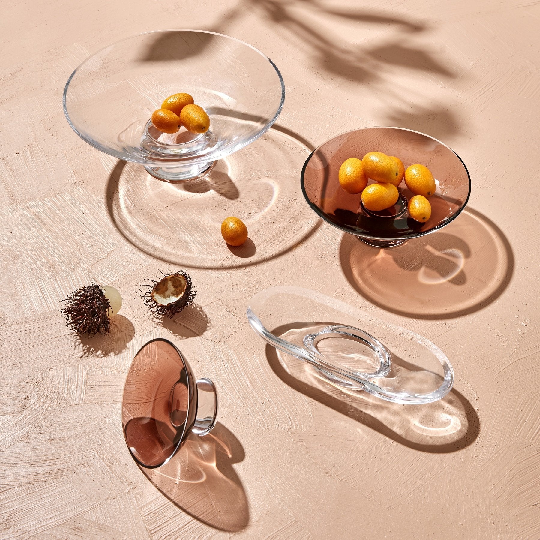 Clear glass bowls with fruits on a textured beige surface