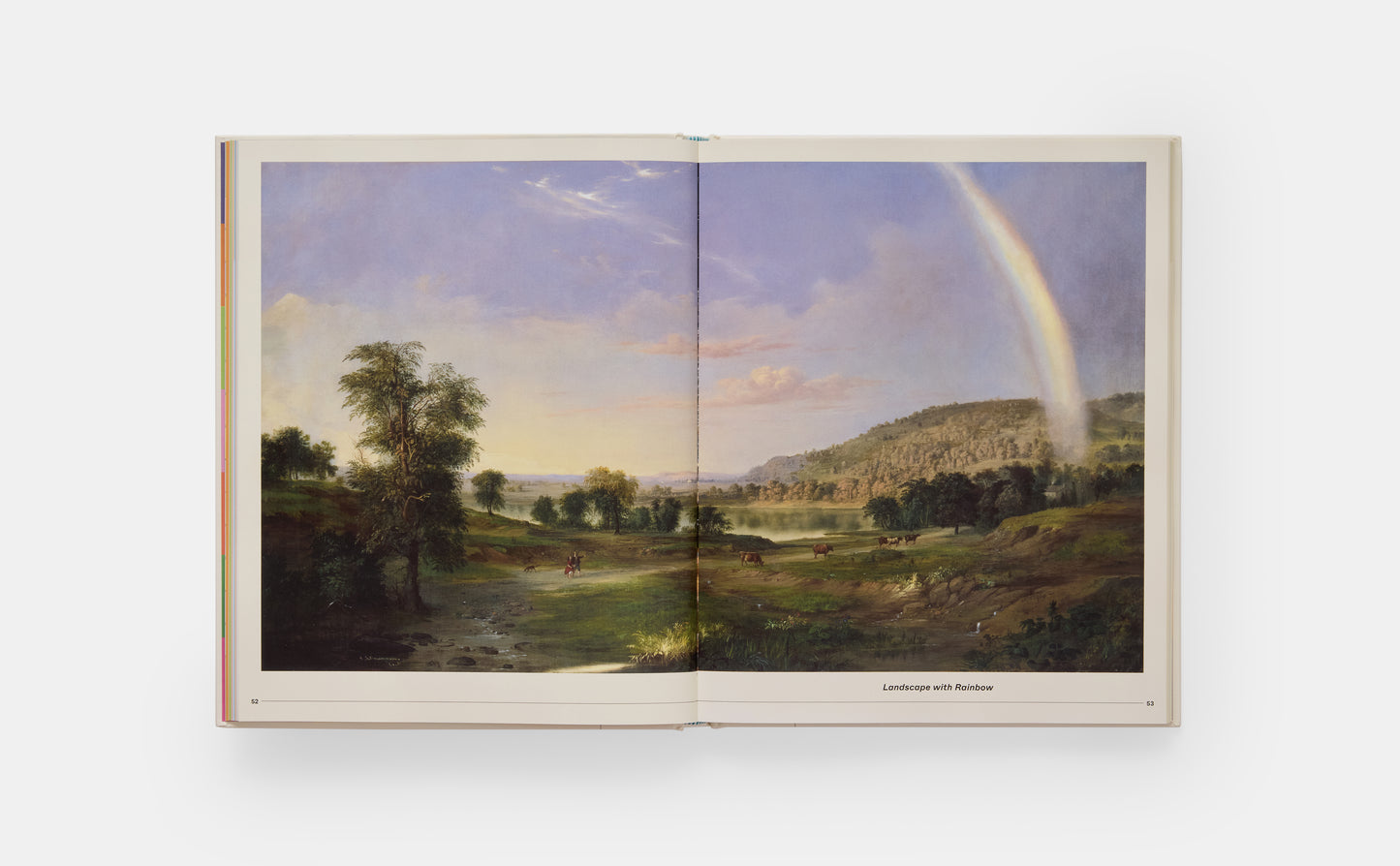 Open book displaying a landscape painting with a rainbow on a white background